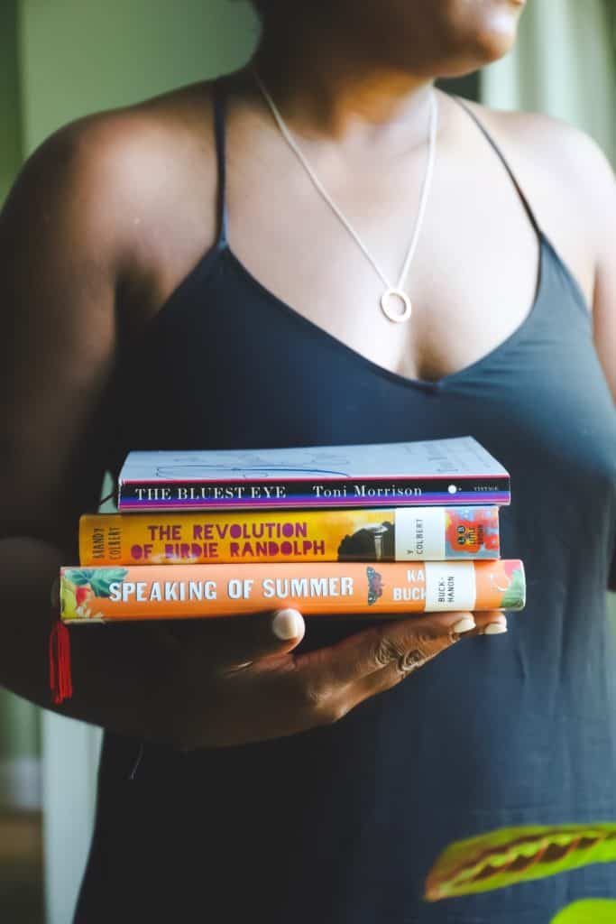 Me holding books for my September reading list talking about Books Beats and Wine Bookclub