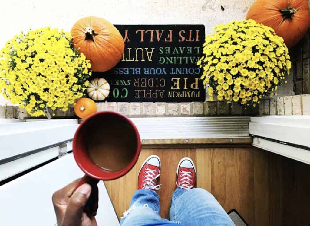 Photo of fall porch decor with coffee and mums and pumpkins. 