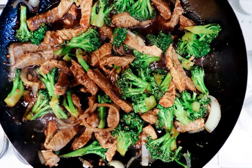 gluten free beef and broccoli being cooked in a wok