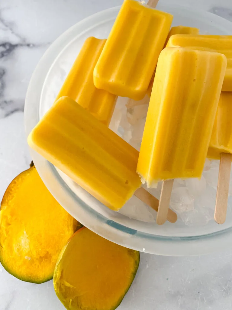 easy mango popsicle recipe with a mango by the platter